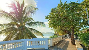 A paved pathway with a white railing, leading to a scenic view of the sea and mountains. - Waterside Inn (Vieques)