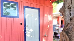 A red building with a white door and a small window. - Waterside Inn (Vieques)