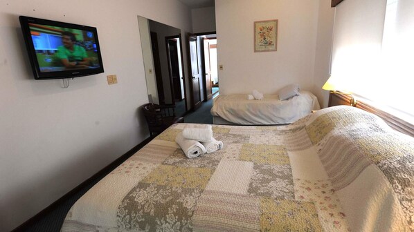 A hotel room with a bed, a TV, a mirror, and a door leading to another room. - Tanger Hotel (Punta del Este)