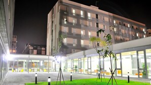 Un edificio moderno con fachada de vidrio, zona de estar al aire libre y un césped cuidado con bolardos.