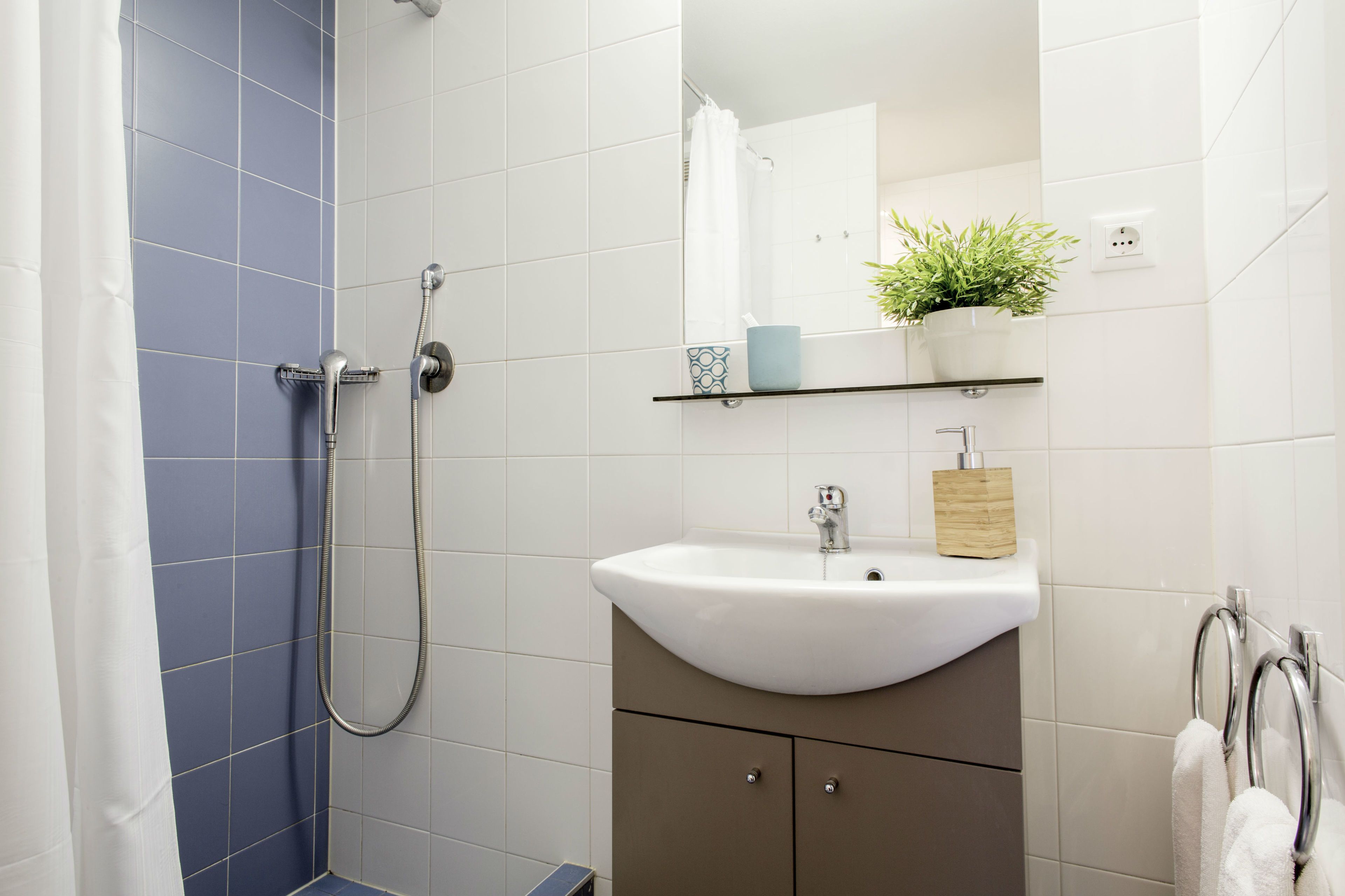 A bathroom with a shower, a sink, and a mirror.