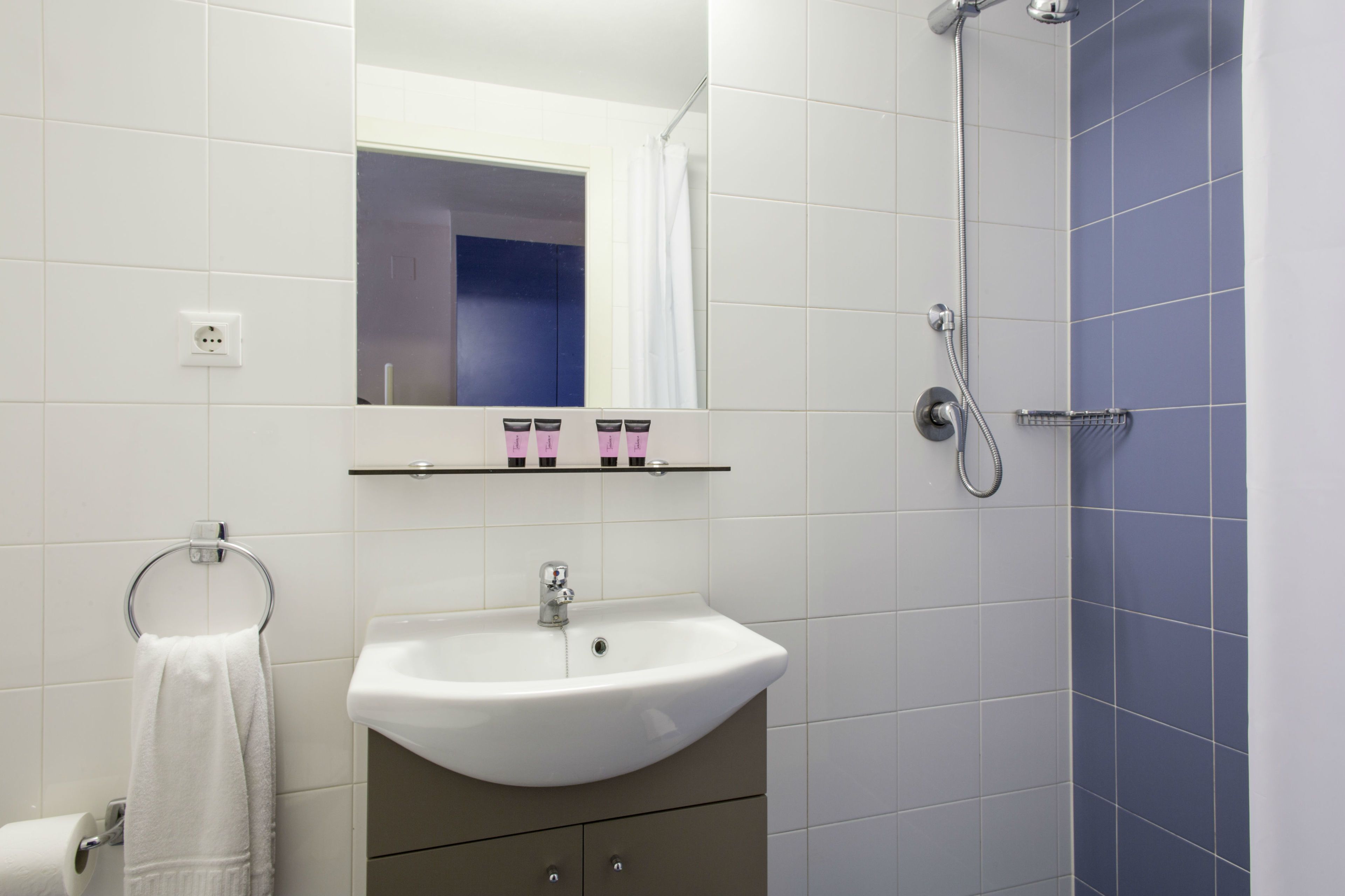 Een badkamer met een witte wastafel, een spiegel en een douche.
