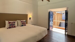 A bedroom with a large bed, wooden beams, a chandelier, and a view of a wooden staircase. - Quinta San Blas by Ananay Hotels (Cusco)