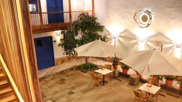 An indoor patio area with stone flooring, wicker furniture, and potted plants. - Quinta San Blas by Ananay Hotels (Cusco)