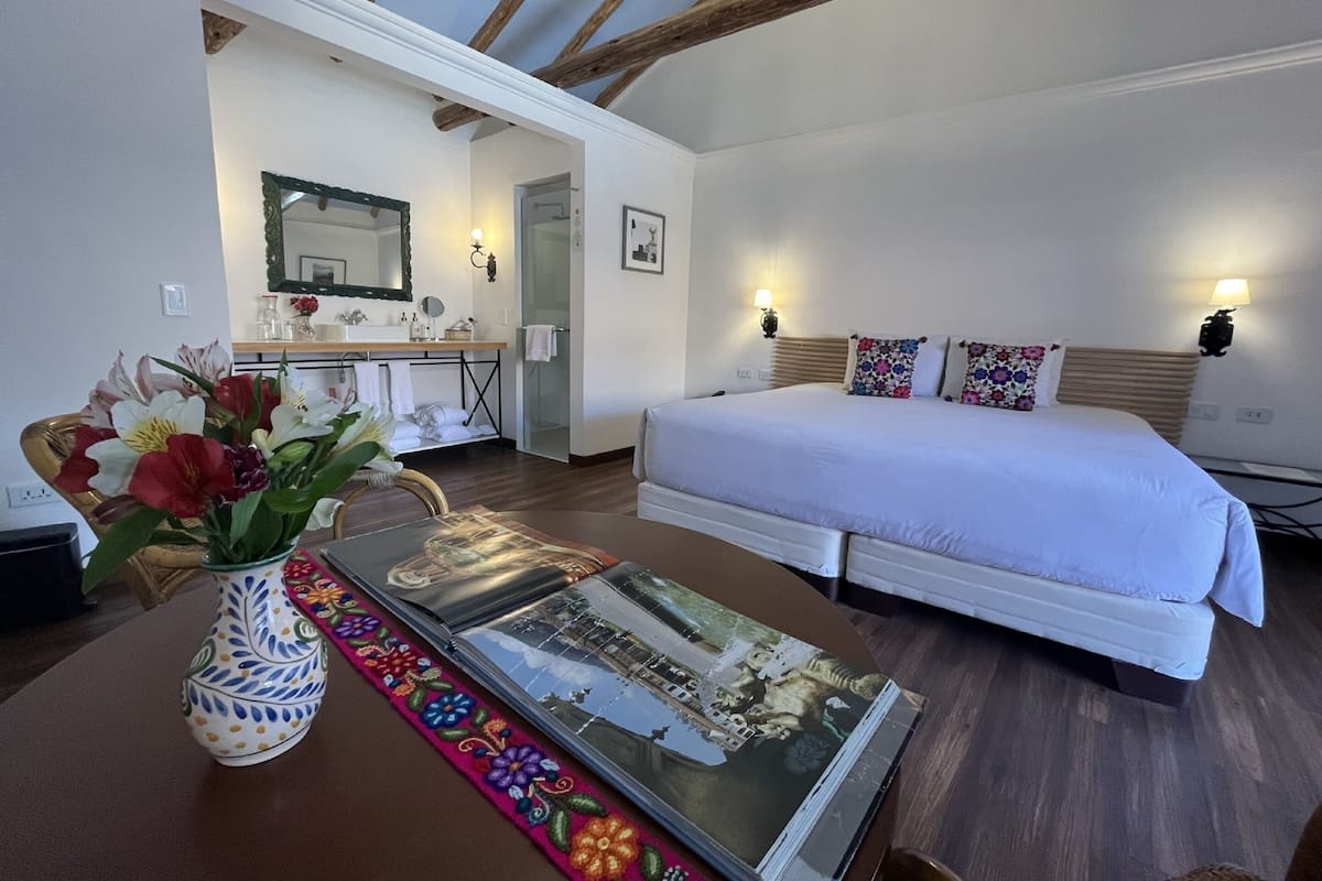 Een slaapkamer met een bed, een nachtkastje, een spiegel en een badkamer zichtbaar door een open deur.