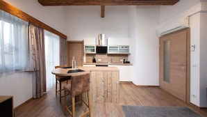 Een moderne keuken met houten balken, een centraal eiland en een eethoek met barkrukken.