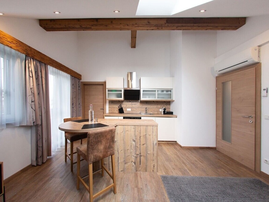 Une cuisine moderne avec des poutres en bois, un îlot central et un coin repas équipé de tabourets de bar.