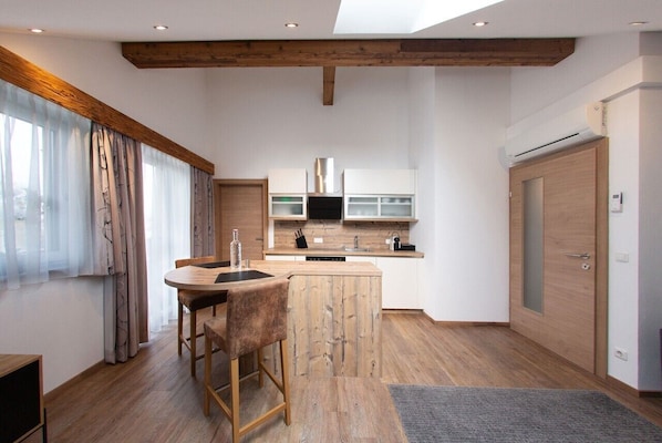 Una cocina moderna con vigas de madera, una isla central y un comedor con taburetes de bar.