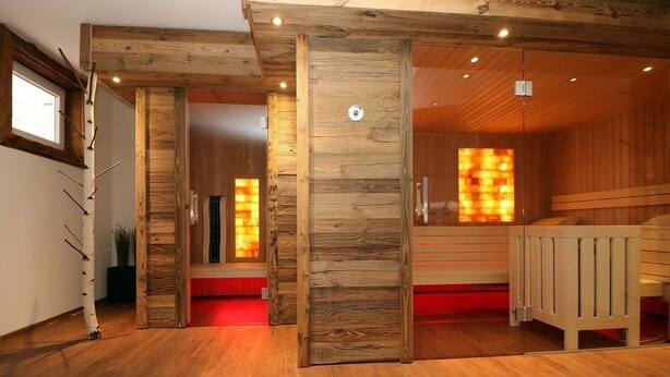 Een houten interieur met een sauna, houten balken en een bank.