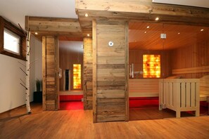 Interior de madera con zona de sauna, vigas de madera y un banco.