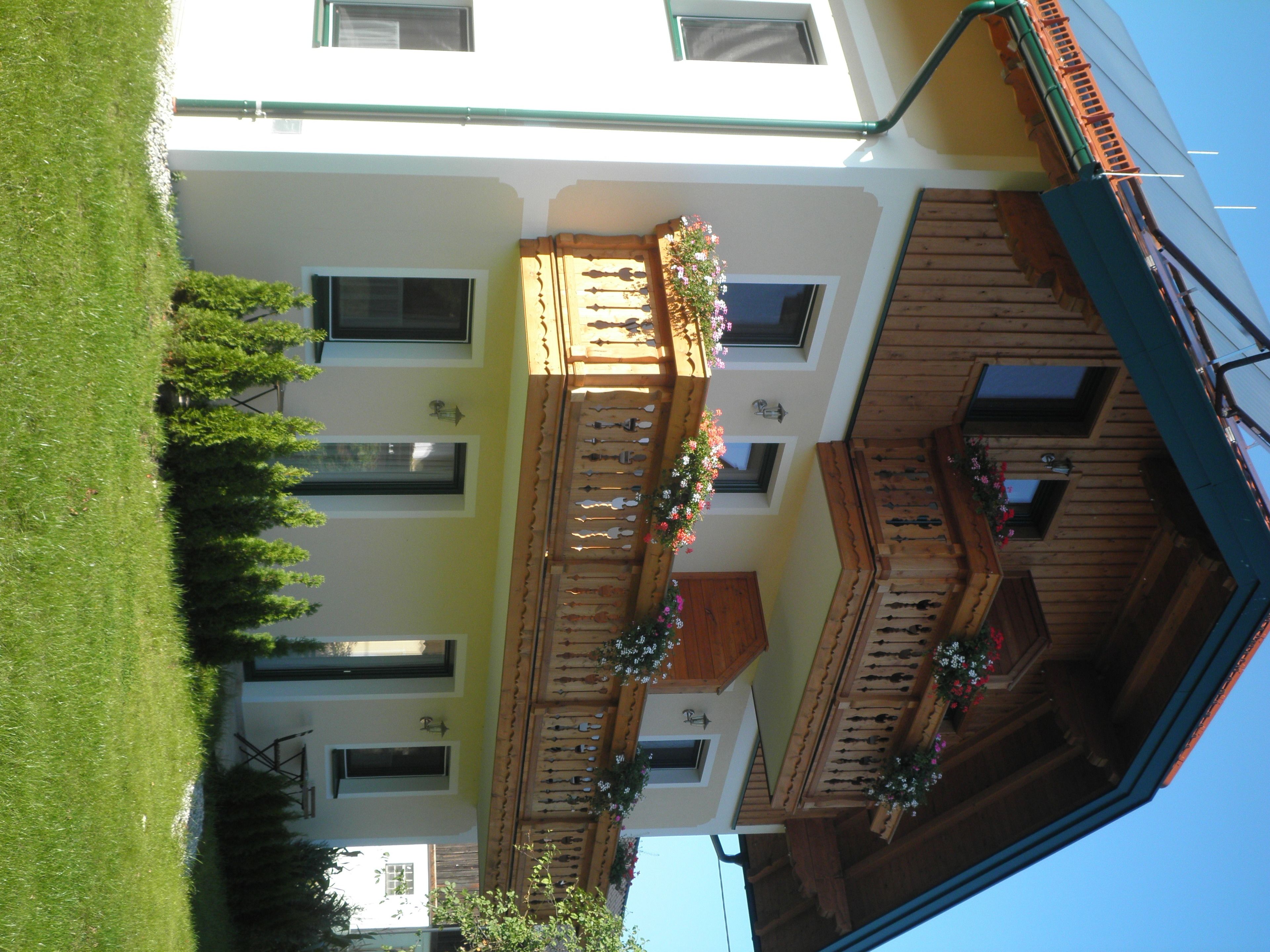Un edificio de varios pisos con balcones, ventanas y un césped verde.