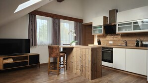 Een moderne keuken met houten kastjes, een ingebouwde oven en een groot raam met gordijnen.