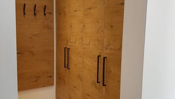 Ein Zimmer mit einem Holzschrank, einer weißen Wand und einem Holzboden.