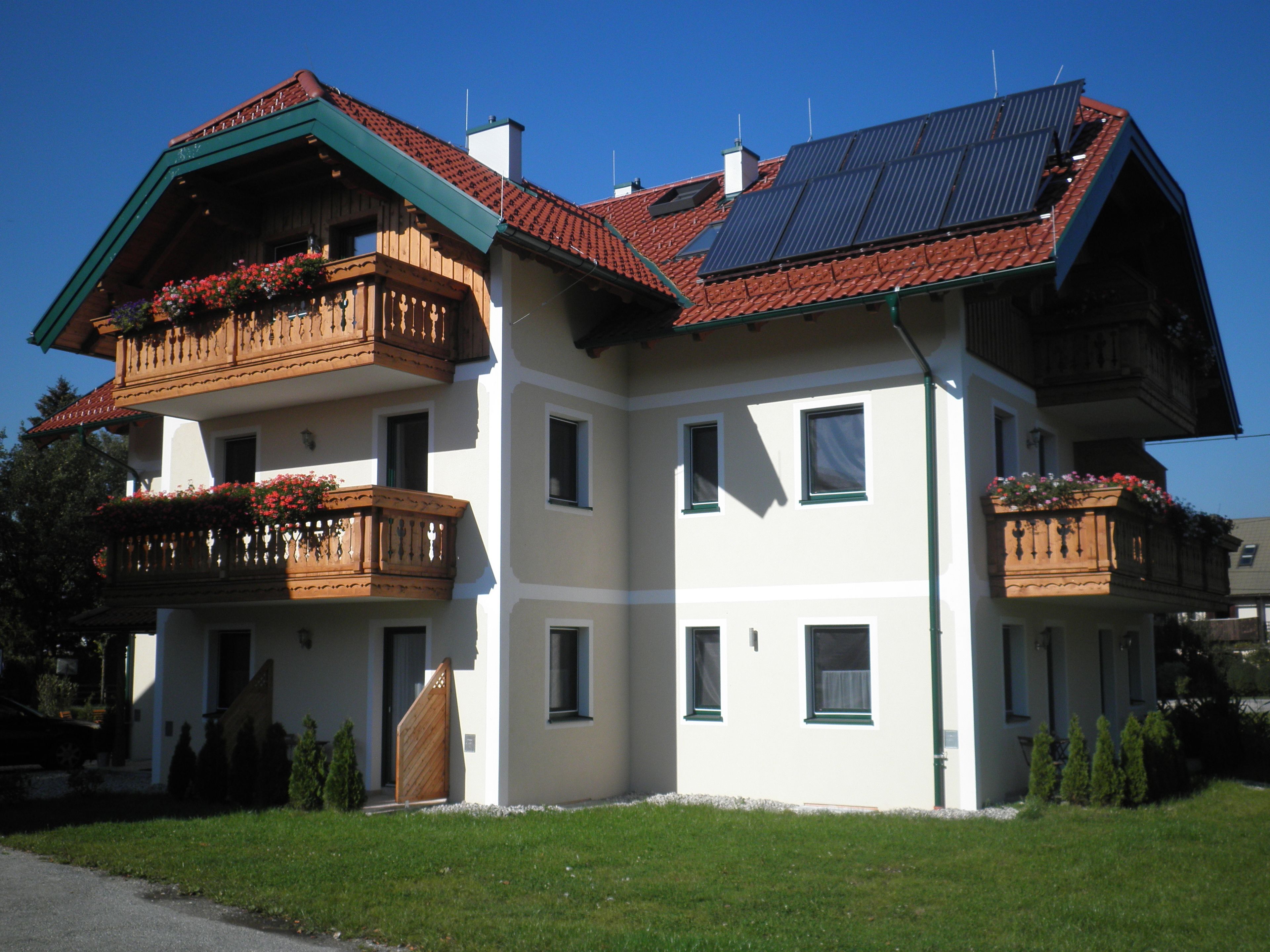 A multi-story building with balconies, solar panels, and a well-maintained lawn.
