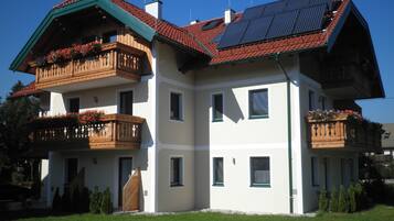 A multi-story building with balconies, solar panels, and a well-maintained lawn.