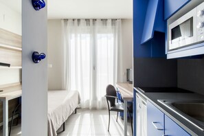Une chambre d’hôtel moderne équipée d’un lit, d’un bureau, d’une chaise, d’un four à micro-ondes et d’un lavabo.