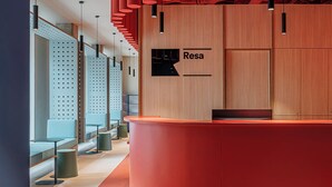 A modern reception desk with a curved design, a wooden panel wall, and a sign that reads "Resa". - Residencia Universitaria Resa La Concepción (Valencia)