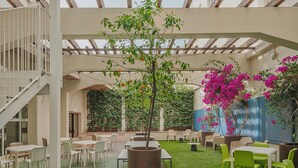 A courtyard with a central tree, surrounding tables and chairs, and a staircase on the left. - Residencia Universitaria Resa La Concepción (Valencia)