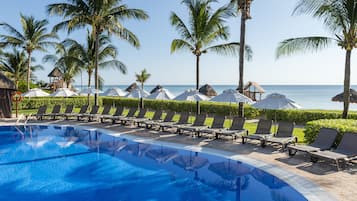 Relax by the oceanfront pool surrounded by lounge chairs and umbrellas.