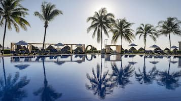 Una piscina al aire libre, sombrillas, sillones reclinables de piscina