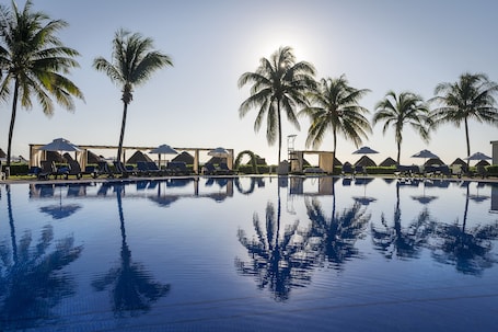 Una piscina al aire libre, sombrillas, sillones reclinables de piscina