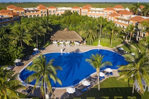 A resort with a central swimming pool surrounded by palm trees and lounge chairs. - El Beso Adults Only at Ocean Coral & Turquesa - All inclusive (Puerto Morelos)