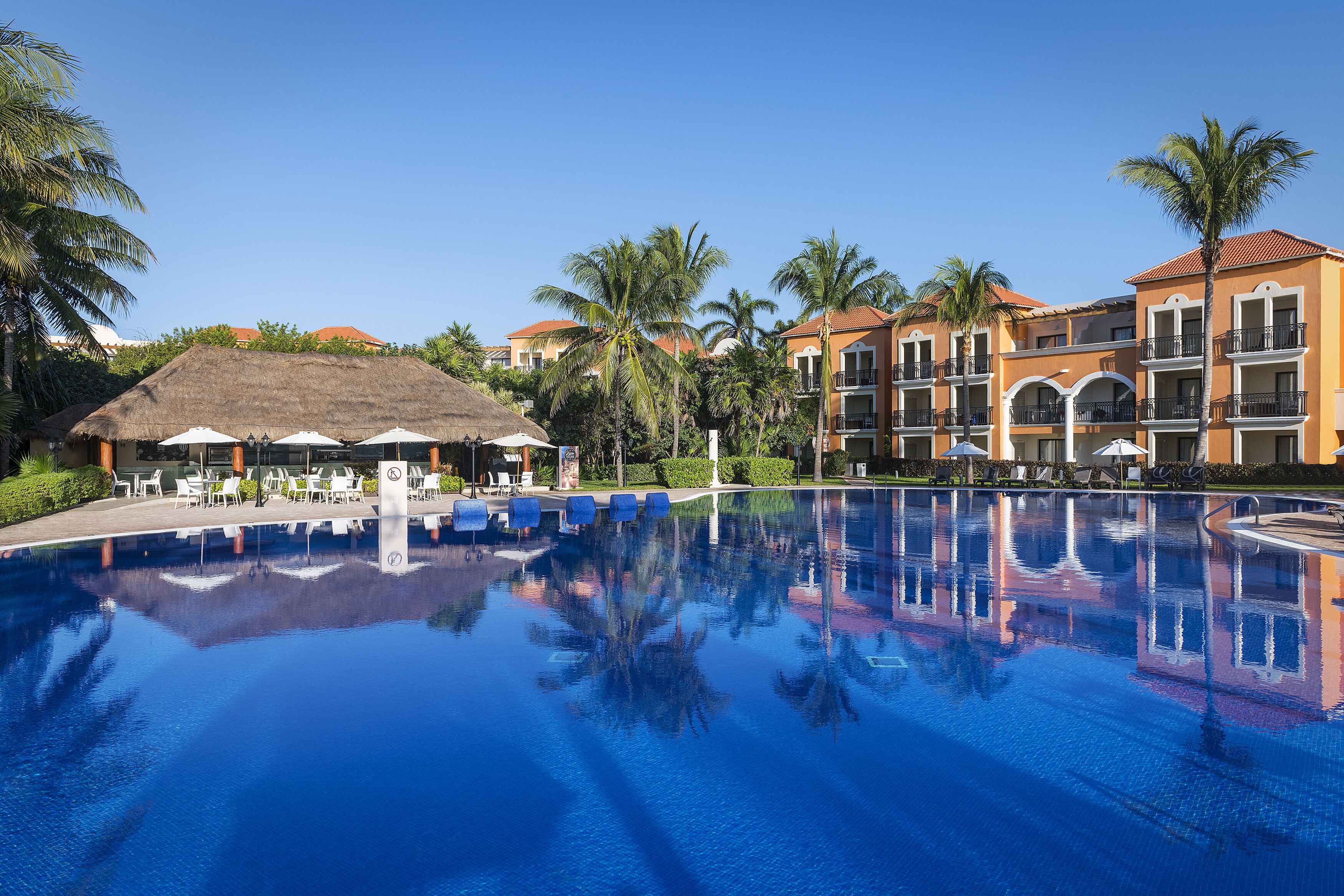 Una piscina al aire libre, sombrillas, sillones reclinables de piscina