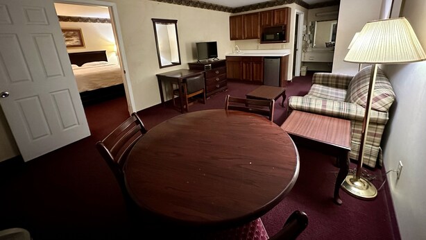 Une chambre d’hôtel compacte comprenant une table à manger, un canapé, une télévision et une kitchenette.