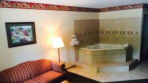 Une salle de bain avec une baignoire, un canapé, une lampe et un tableau encadré au mur.