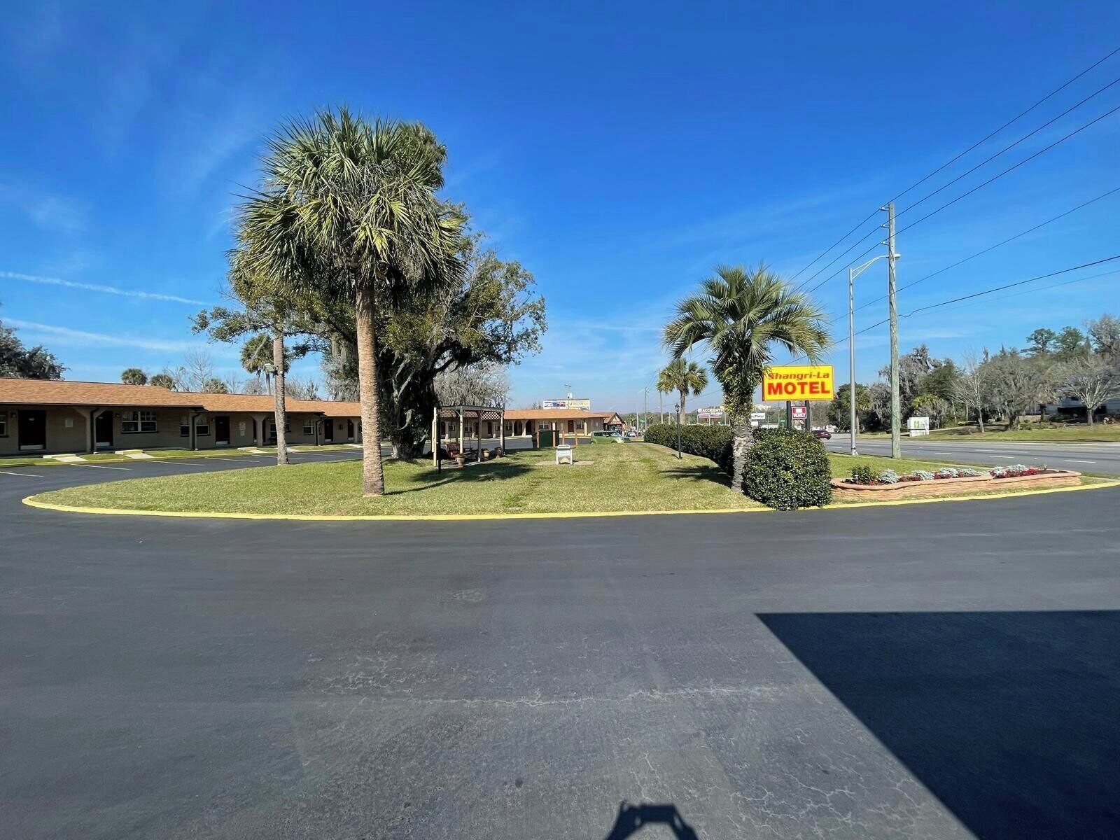 Un motel con estacionamiento, una zona de estar al aire libre techada y un letrero que dice Shangri-La Motel.