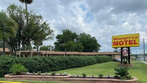 Un motel con un letrero, césped y un edificio con porche.