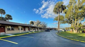 A motel with a parking lot, a row of rooms, and palm trees. - Shangri La Motel  (Ocala)