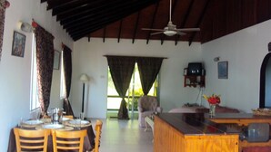A dining area with a wooden table and chairs, a bar area with a wooden counter, and a ceiling fan.