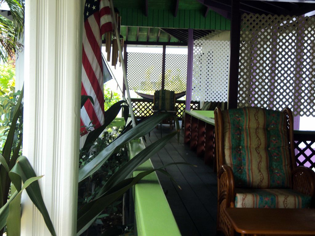 Un espace extérieur abrité comprenant un banc vert, une chaise à motifs et un drapeau américain.