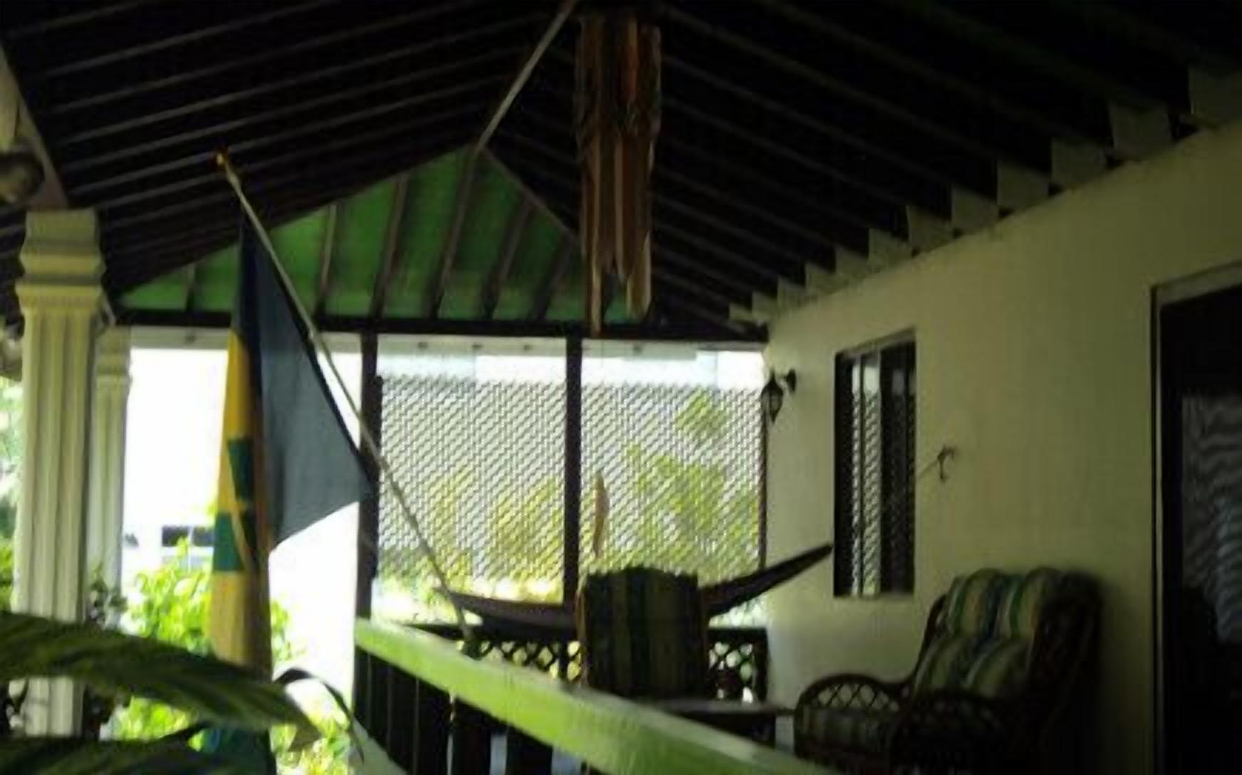 A covered outdoor area with a hammock, a chair, and a table.
