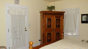 Un dormitorio con cama, armario, puerta con letrero de 'SALIDA' y ventana con cortina.