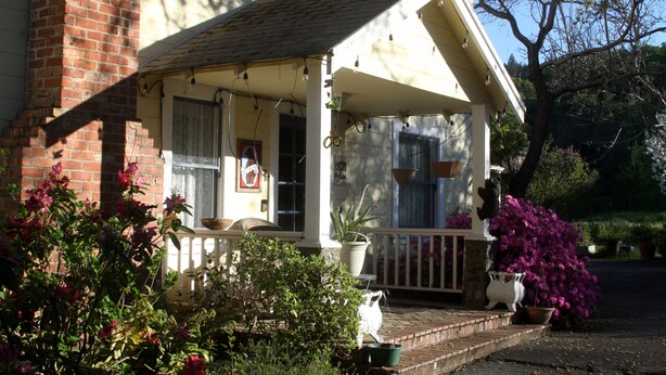 A house with a porch, potted plants, and a brick wall. - Bear Flag Inn (Calistoga)
