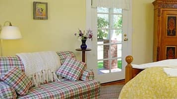 A cozy room with a plaid sofa, a small table with a vase of flowers, and a wooden cabinet.