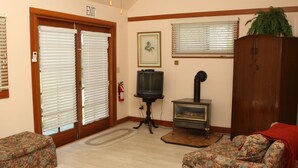 A living room with a fireplace, two sofas, a television, and a door marked 'EXIT'. - Bear Flag Inn (Calistoga)
