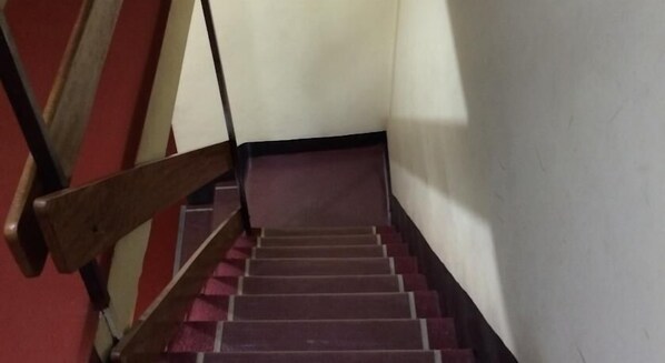 A staircase with wooden handrails and a red carpeted floor.