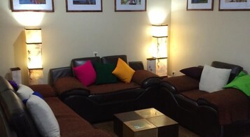 Una sala de estar con un sofá marrón, una mesa de centro y cuadros enmarcados en la pared.