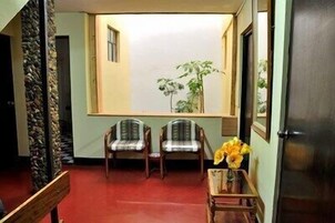 Una habitación con dos sillas, una mesita con un jarrón de flores y una ventana con vista a zonas verdes.