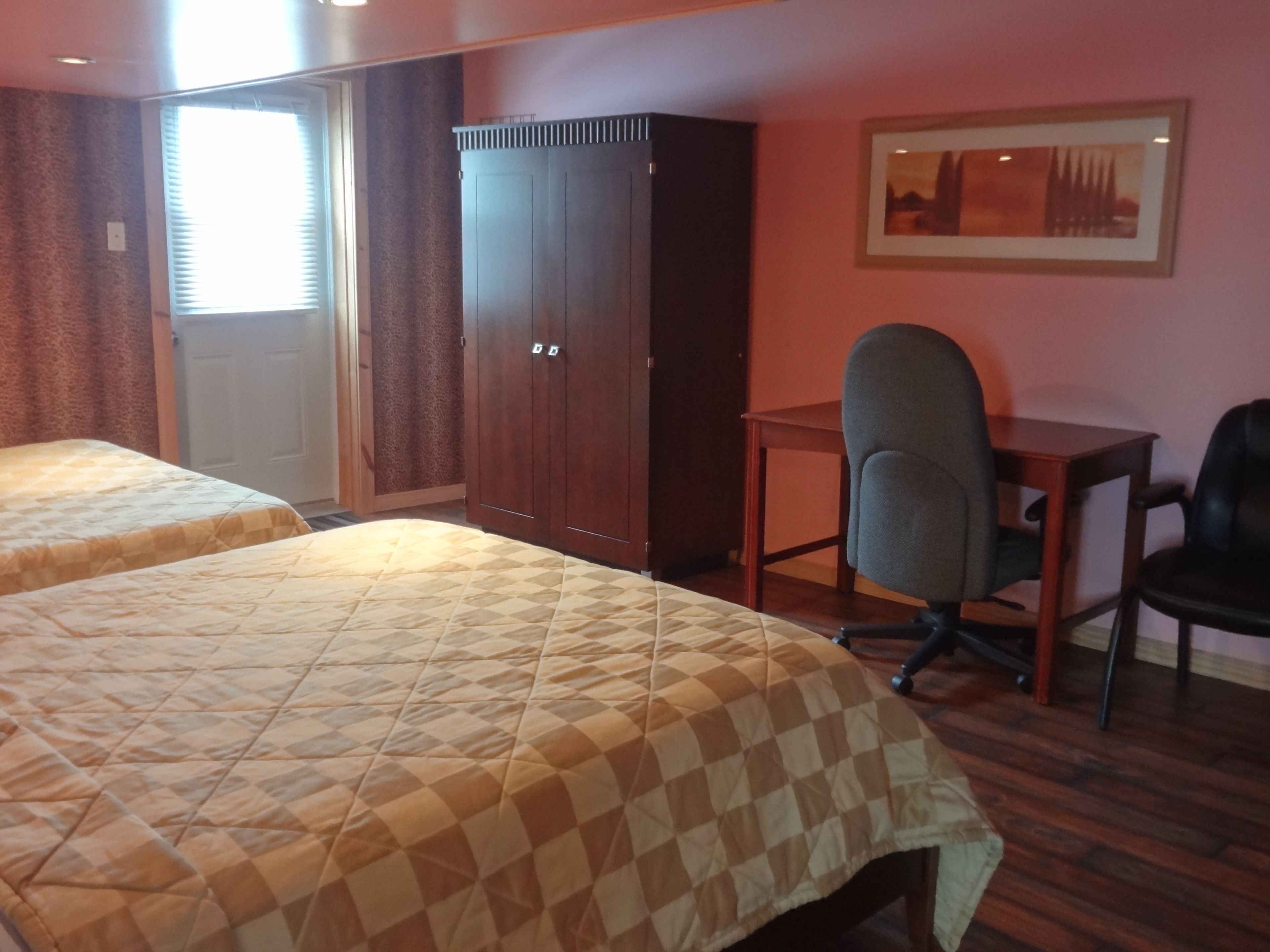 Een hotelkamer met twee bedden, een bureau, een stoel en een kledingkast.
