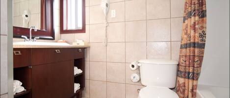 Baño con lavamanos, espejo, toallero, inodoro y cortina de ducha.