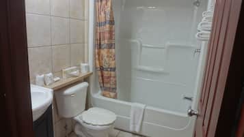 Et badeværelse med toilet, vask, badekar og brusenik.