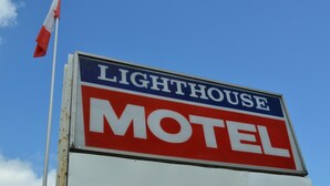 A sign for a lighthouse motel with a red and white color scheme.