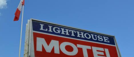A sign for a lighthouse motel with a red and white color scheme.