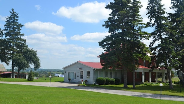 A two-story building with a red roof, surrounded by green lawns and trees.