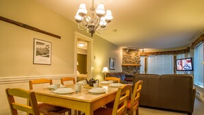 Comedor con mesa de madera dispuesta para cuatro personas, una araña y una pared de acento de piedra.