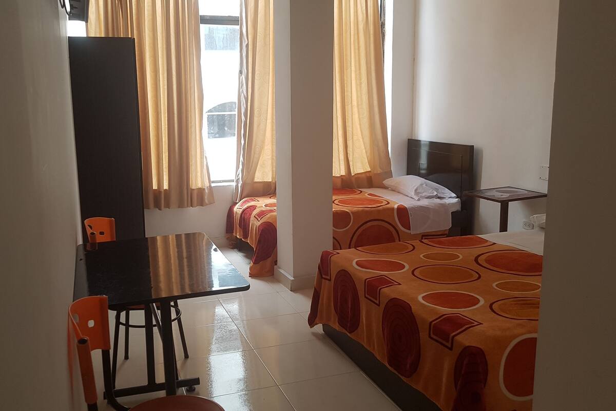 A hotel room with two beds, a desk, and a chair.